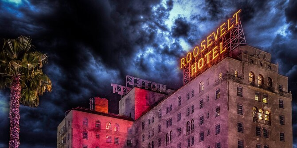 LA Roosevelt Hotel stands lit up against a stormy sky